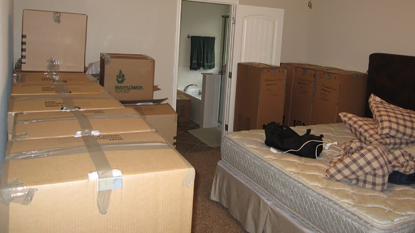 Bedroom full of stacked moving boxes before removal